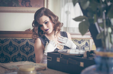 Young beautiful woman in retro style near a vinyl record player. Vintage interior.