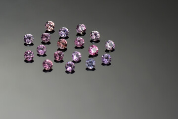 Round shaped natural fancy color sapphires lot. Classic diamond cut, faceted. Pink, violet purple hues small loose gems for jewelry making. Gray gradient background. Gemology theme. 