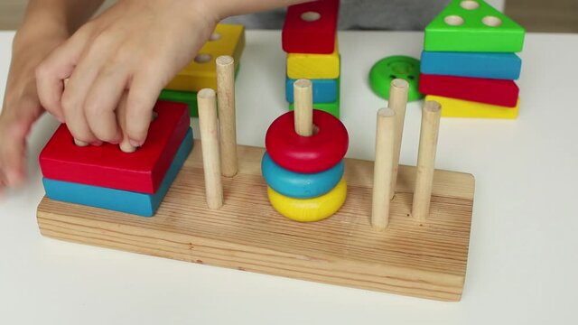 A child playing with a children's educational wooden toy. Preschool education. Study of colors. Montessori concept, early brain exercise. Multicolored logic sorter.	
