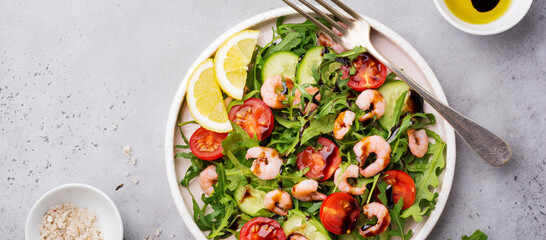 Arugula, cucumber, tomato and shrimp salad with soy sauce on a ceramic plate. Selective focus. Top view