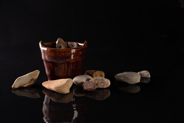 Stones and ceramic vase on black background