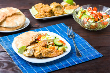 Baked fish served with vegetable salad with feta cheese