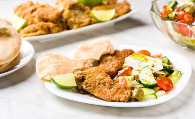 Baked fish served with vegetable salad with feta cheese
