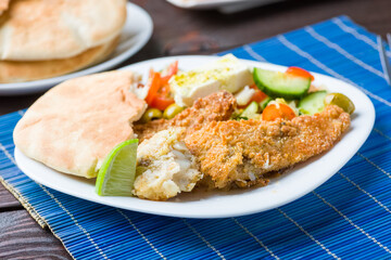 Baked fish served with vegetable salad with feta cheese