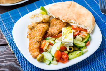 Baked fish served with vegetable salad with feta cheese