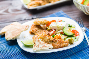 Baked fish served with vegetable salad with feta cheese