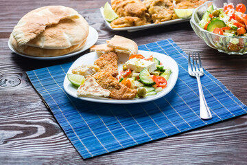 Baked fish served with vegetable salad with feta cheese