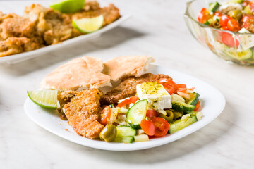 Baked fish served with vegetable salad with feta cheese