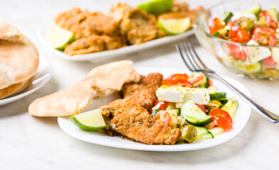 Baked fish served with vegetable salad with feta cheese