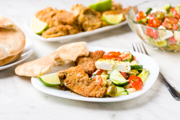 Baked fish served with vegetable salad with feta cheese