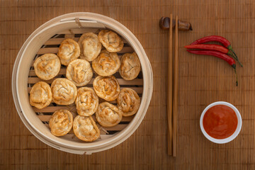 Fried dumplings, dumpling with sauce, chopsticks and red hot peppers on a bamboo mat. Asian street food. View from above
