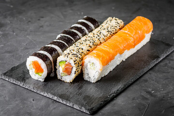 appetizing set of sushi roll on a black stone plate
