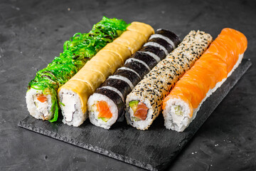 appetizing set of sushi roll on a black stone plate