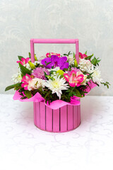 Beautiful bouquet of bright flowers in a basket, on a table in a restaurant
