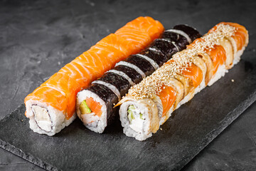 appetizing set of sushi roll on a black stone plate