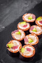 appetizing sushi roll with tuna salmon escolar crab and avocado on a black stone plate