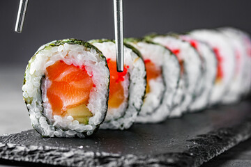appetizing sushi roll maki with salmon on a black stone plate © Narsil