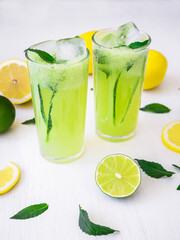 Fresh refreshing drink with cucumber, lime and lemon on table