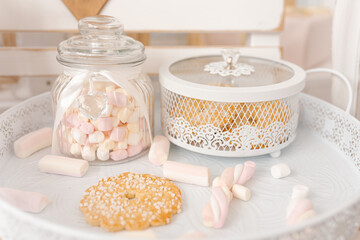Delicate decor. From cookies and marshmallows. On white lace tray. Glass jar tied with bow. Concept of Christmas.