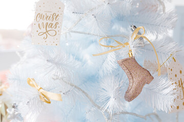 White Christmas tree decorated with silver golden pink Christmas balls and beautiful gold boot on sparkling and fairy white blue branch, decorative lights, with beautiful bokeh, copy space.