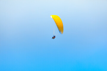 Paragliding at the blue sky . Flying Paraglider extreme sport . Yellow parachute