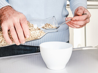 Handsome man preparing a healthy breakfast. Close-up, indoors. Day light, studio photo. Concept of healthy and delicious food