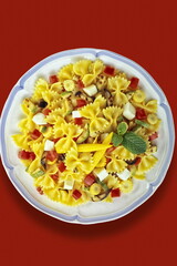 farfalle with white cheese, corn and tomato pieces seen from above