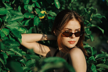 cheerful fashionable woman in sunglasses and green leaves russian summer