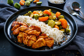 Fried chicken nuggets with white rice, brussels sprouts, carrots and tangerines on wooden table
