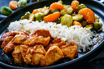 Fried chicken nuggets with white rice, brussels sprouts, carrots and tangerines on wooden table
