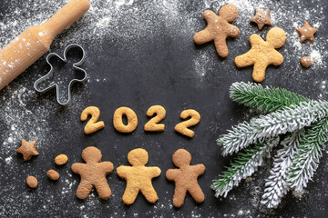 Gingerbread men and a branch of a Christmas tree. New Year's background. 2022 year.