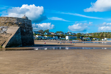 A view past the harbour wall towards the front beach at Saundersfoot, South Wales on a sunny day - obrazy, fototapety, plakaty