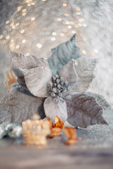 Christmas poinsettia flower and blurred light beautiful background with yellow bokeh. Toned image. Dry flowers, mirror balls.