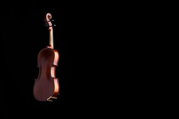 A violin or viola with four strings with a beautiful soft light hitting it on a black background....