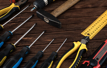 Locksmith's working tool. Mechanical assembly and disassembly tool. Screwdrivers, pliers, wire cutters, building level, tape measure, hammer, wrenches, square and other tools on a wooden surface.