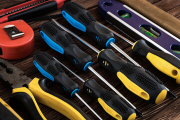 Locksmith's working tool. Mechanical assembly and disassembly tool. Screwdrivers, pliers, wire cutters, building level, tape measure, hammer, wrenches, square and other tools on a wooden surface.
