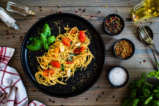 Spaghetti aglio e olio with parmesan, cherry tomatoes and basil on wooden table

