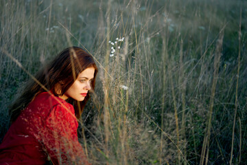 woman in the field lies on the grass in a red dress posing
