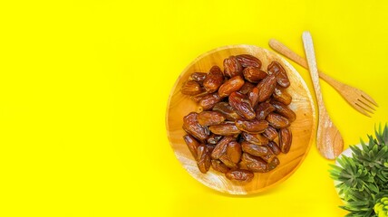 Fresh and healty premium honey tunisia dates (kurma tunisia) in a wooden bowl isolated on yellow background