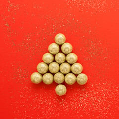New Year and Christmas card. Christmas tree from golden Christmas balls on a bright red background. Minimal Christmas concept