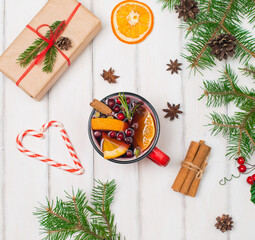 Christmas white wooden background with mulled wine in red mug, Christmas gift box, anise and spruce branches. Top view with copyspace.