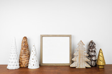 Christmas mock up with wood frame and rustic tree decor. Square frame on a wood shelf against a...