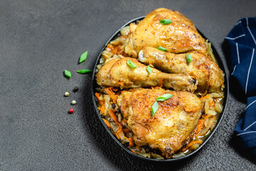 Oven roasted chicken with vegetables on dark background in cast iron skillet. Space for text.