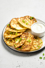 Cheesy zucchini pancakes with yogurt sauce. Space for text.