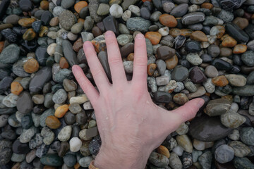 Hand touching stones by the sea