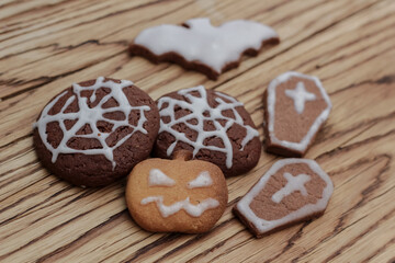 Funny chocolate gingerbread and ginger cookies in the form of a bat, coffins and pumpkin lantern for Halloween on wooden table. horizontal view from above