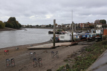River Thames at Hammersmith at low tide with boats houses and rowers