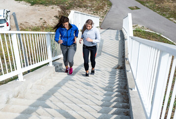 Two young active woman workout run up the stairs in a sports wardrobe trains for a healthy life and prepares herself as a marathon runner. Sporty female exercise in the morning before they go to work.