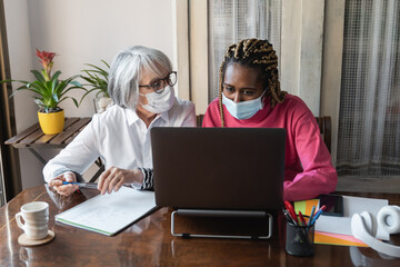 Multiracial senior and young business people working together wearing safety masks at home office