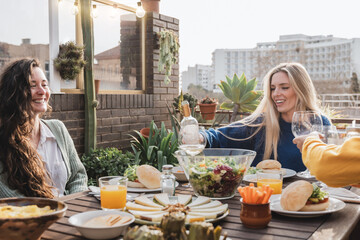 Happy friends eating vegan food with wine outdoors at patio restaurant - Focus on center girl face